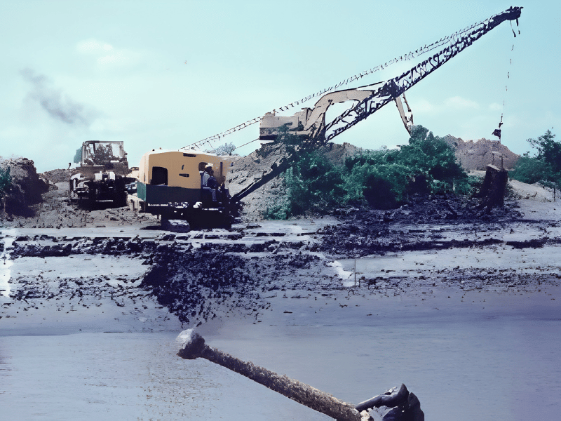 Heavy machinery installing pipeline across marshy terrain