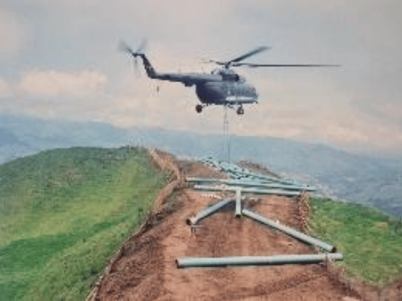 Helicopter supporting pipe laying in mountainous terrain