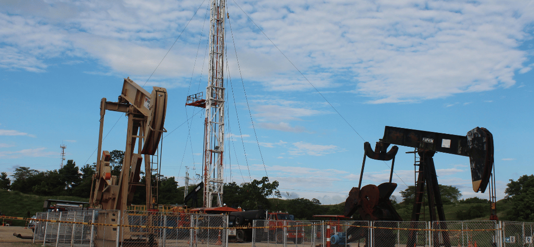 Pump jacks and a drilling derrick in a producing oil field