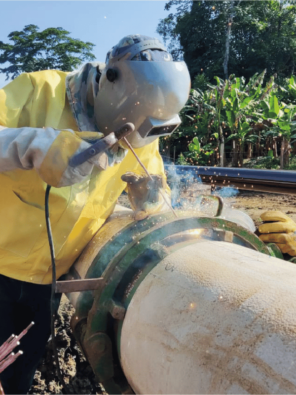 Worker applying coating to a pipeline in the field
